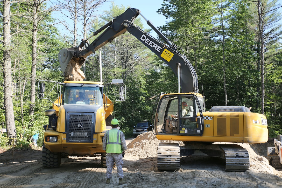 CAMP WILLIAM HINDS, RAYMOND, Maine – Reserve Marines from 6th Engineer Support Battalion use an excavator to move large mounds of dirt into a dump truck after digging an underdrain for water runoff for the Boy Scouts of America during the joint service Innovative Readiness Training on Camp William Hinds in Raymond, Maine, July 10, 2014. IRT Camp Hinds is a joint service initiative designed to provide service memebers with real-world training opportunities preparing them for their war-time missions while also supporting the needs of America’s underserved communities. (Photo by Sgt. Adwin Esters/Released 140710-M-JL916-018)