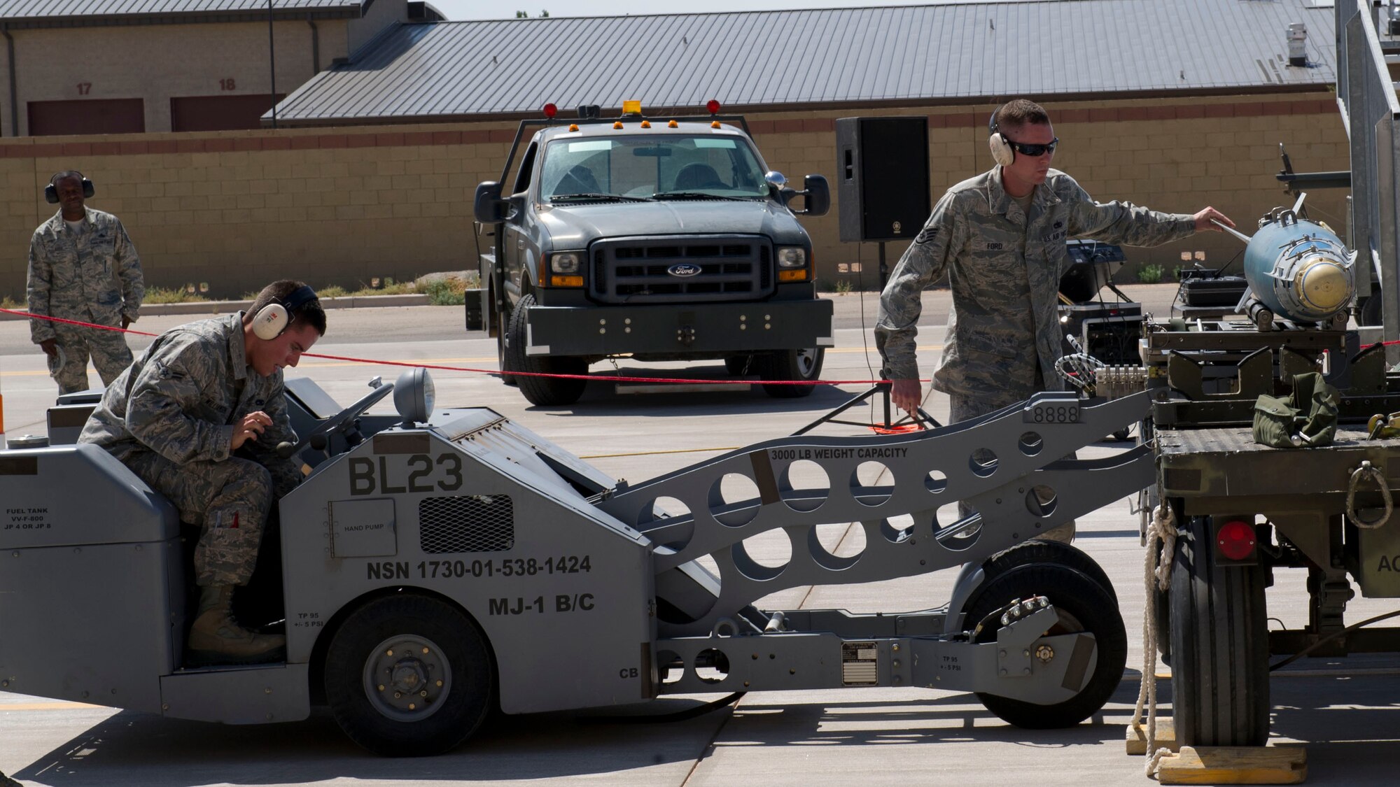 Airman 1st Class Christopher Williamson and Staff Sgt. Dustin Ford, 49th Maintenance Group MQ-9 Reaper weapons load crew 58 members, prepare to transport a GBU-12 Paveway bomb during the third quarterly load crew competition at Holloman Air Force Base, N.M., July 11. The MQ-9 load crew participated in the competition to have their skills evaluated alongside the F-16 Fighting Falcon load crews. For the competition, points are awarded for weapons-loading, toolkit inspection, and uniform inspection. (U.S. Air Force Staff Sgt. E’Lysia A. Wray/Released)