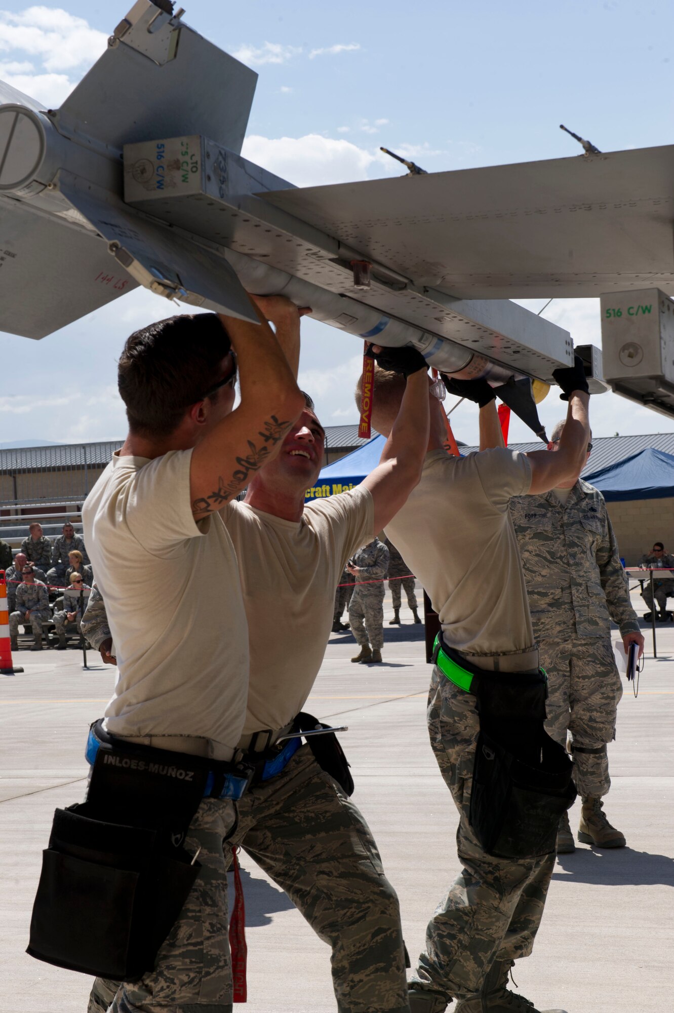 Senior Airman Nicholes Munoz, Staff Sgt. Joshua Hood and Senior Airman Joshua Parker, 54th Fighter Group F-16 Fighting Falcon weapons load crew 102 members, load an inert AIM-9 Sidewinder missile during the third quarterly load crew competition at Holloman Air Force Base, N.M., July 11. The F-16 load crew participated in the competition to have their skills evaluated alongside the MQ-9 Reaper load crews. For the competition, points are awarded for weapons-loading, toolkit inspection, and uniform inspection. (U.S. Air Force Staff Sgt. E’Lysia A. Wray/Released)