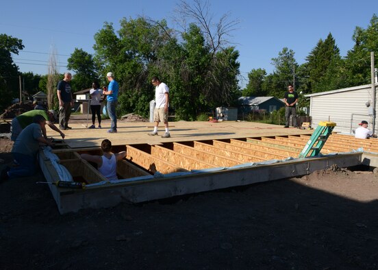A dozen Malmstrom Air Force Base Airmen work together to lay plywood down for the subfloor of unit 31, a Habitat for Humanity home in Great Falls, Mont., July 12. Approximately 25 families are on the waiting list to receive a home, which takes nine months to build. (U.S. Air Force photo/Senior Airman Katrina Heikkinen)