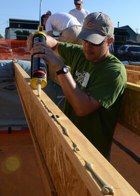 Capt. Jason Garcia, 341st Medical Support Squadron diagnostics and therapeutics flight commander, puts construction adhesive glue on a floor joist before laying down plywood. Airmen from Malmstrom Air Force Base volunteered six hours to complete the subfloor for unit 31, a Habitat for Humanity home. (U.S. Air Force photo/Senior Airman Katrina Heikkinen)