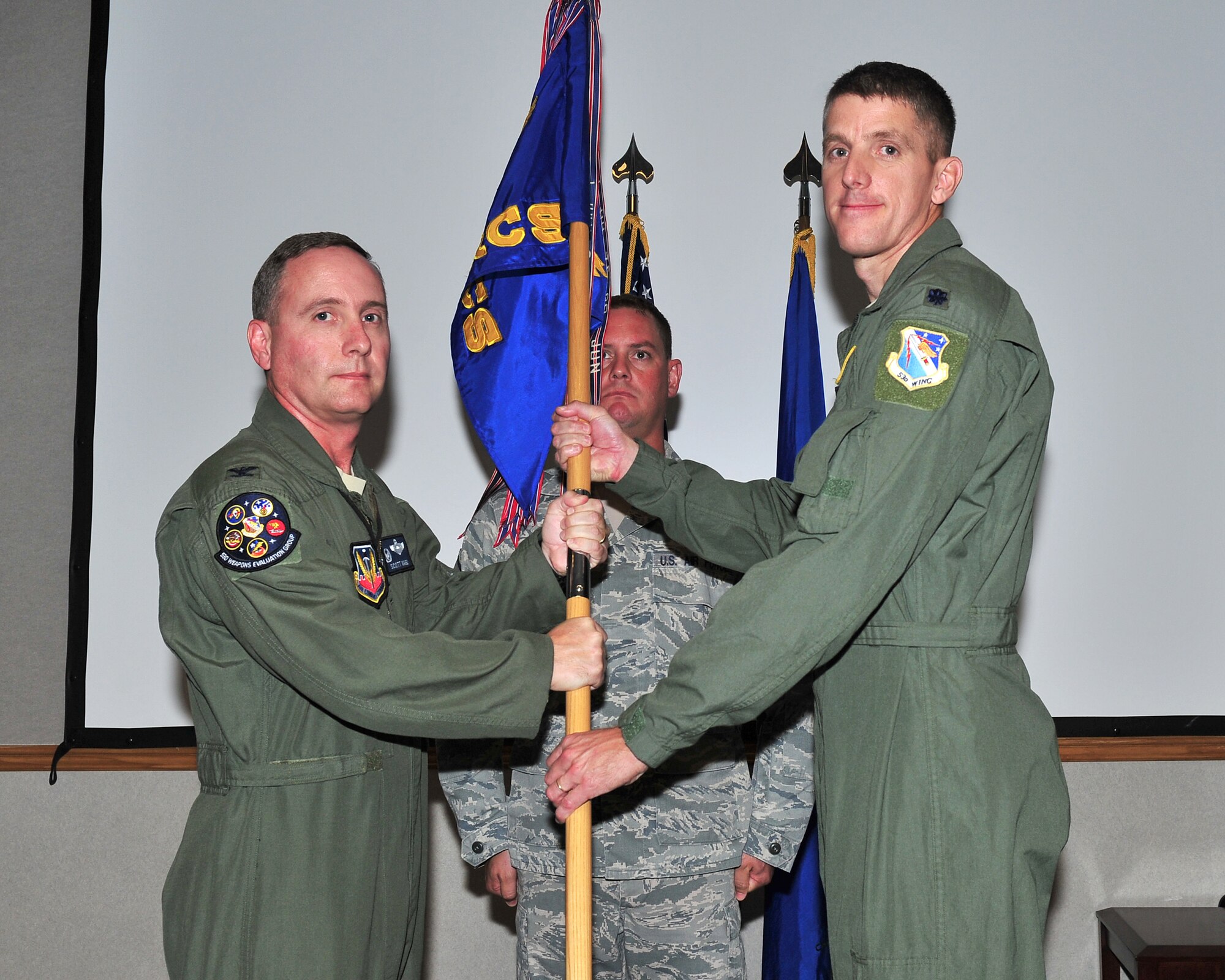 Colonel Scott Ward, 53rd Weapons Evaluation Group commander, passes the 81st Range Control Squadron guidon to Lt. Col. James Wilson who assumed command of the 81st RCS in a change of command ceremony July 11. (U.S. Air Force photo by Senior Airman Danielle Colberg)