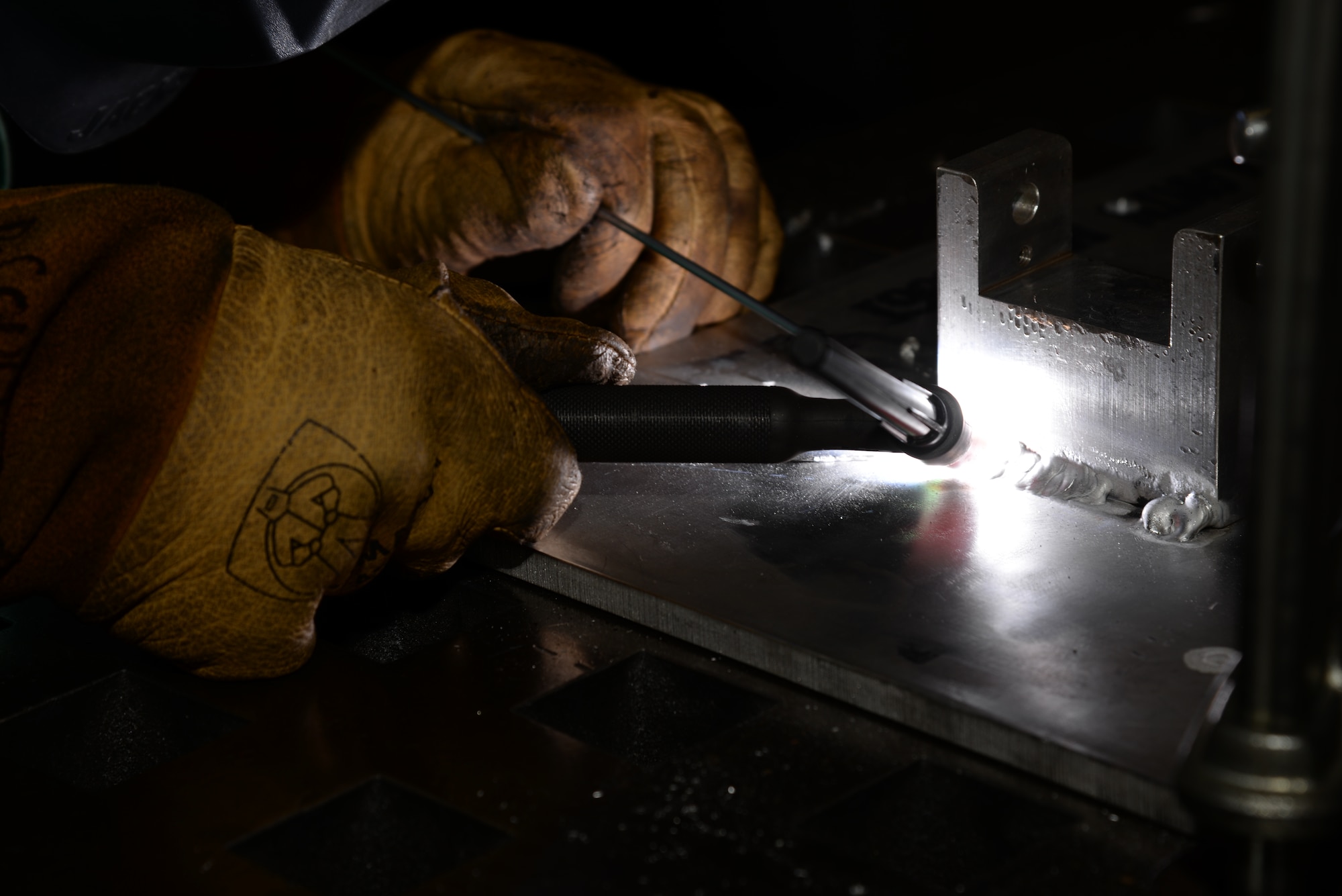 Senior Airman Deryc Coulson, 23d Equipment Maintenance Squadron fabrications flight aircraft metals technology journeyman, heats aluminum to more than 1,200 degrees Fahrenheit to weld the maintenance stand of a .50-caliber machine gun July, 11, 2014, at Moody Air Force Base, Ga. The 23d Equipment Maintenance Squadron fabrications flight frequently interacts with the heated materials to make repairs to aircraft and maintenance parts. (U.S. Air Force photo by Staff Sgt. Eric Summers Jr./Released)