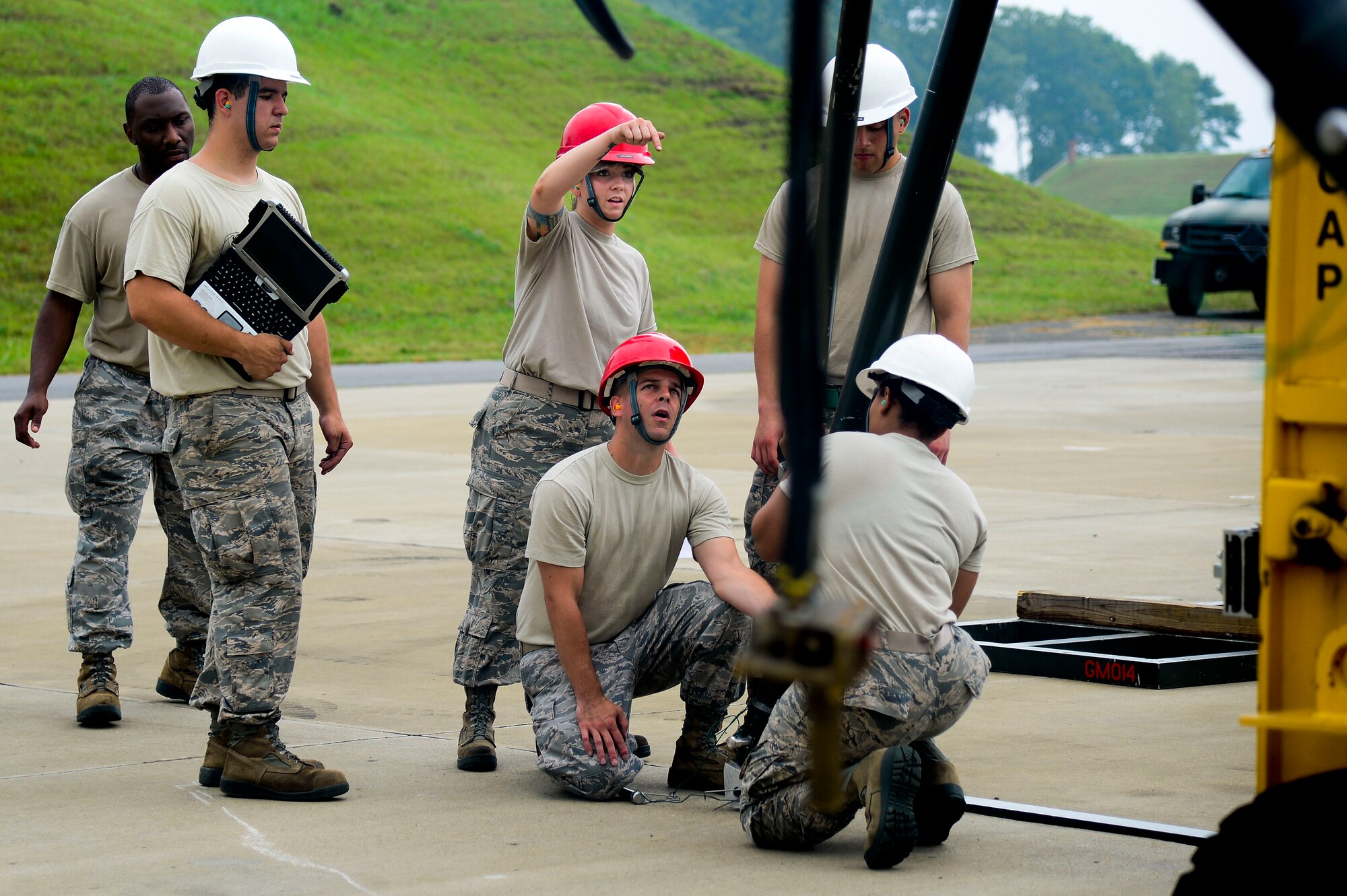 U.S. Air Force Staff Sgt. Victoria Yale, 2014 Air Combat Command Munitions Supervisor of the Year, assists members of the 1st Maintenance Squadron in building a munitions assembly conveyer at Langley Air Force Base, Va., June 12, 2014. Yale said she leads by example so young Airmen can see and experience what being a good munitions Airman means. (U.S. Air Force photo by Senior Airman Kayla Newman/Released) (photo cropped and color corrected for effect)
