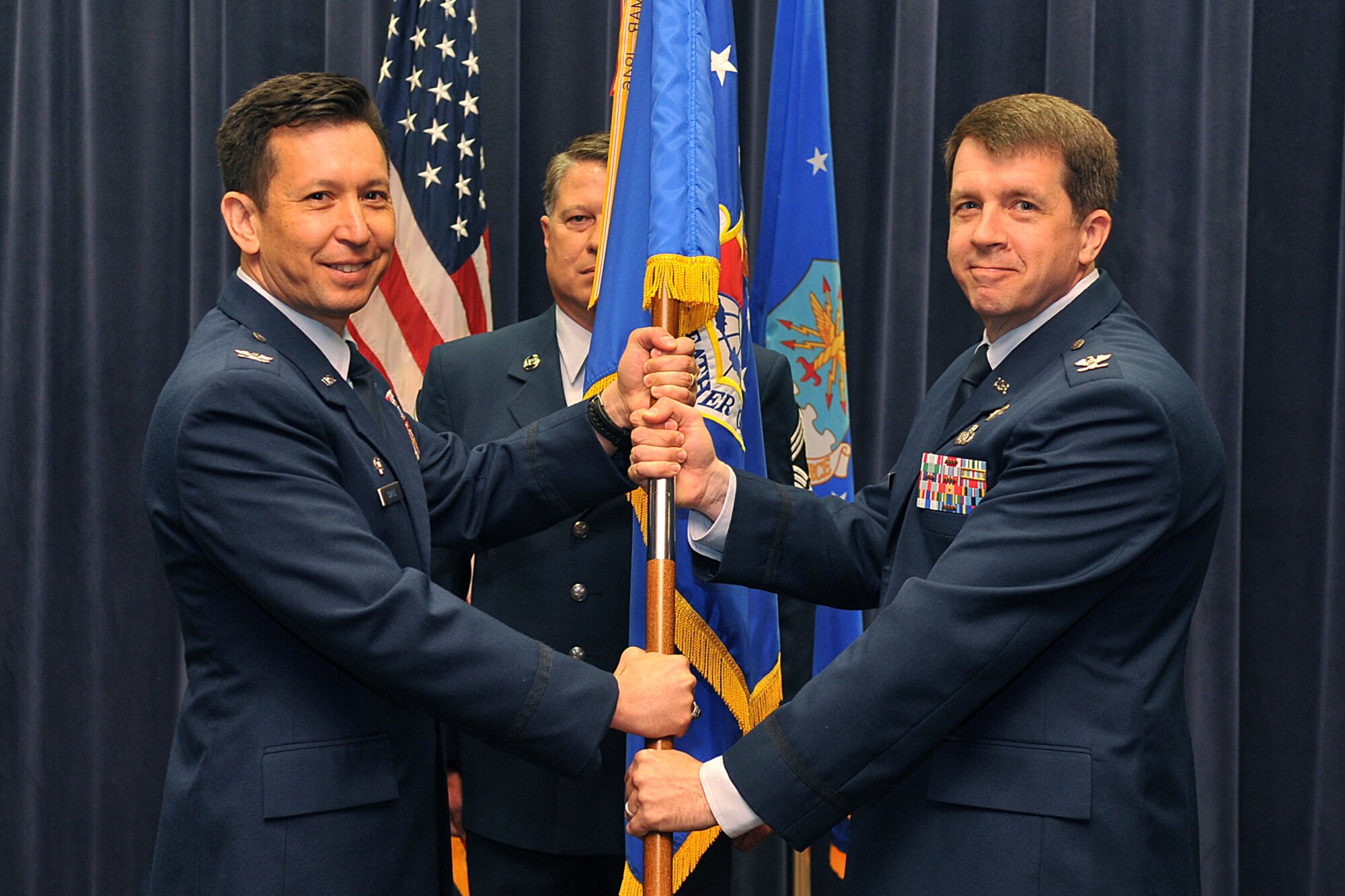 U.S. Air Force Col. William Carle, Air Force Weather Agency commander, hands the 2d Weather Group guidon to U.S. Air Force Col. Donald Shannon during the 2d WXG change of command ceremony July 8 at the AFWA Headquarters Building on Offutt Air Force Base, Nebraska. Shannon took command from U.S. Air Force Col. David Bacot, who will go on to be the AFWA vice commander. (U.S. Air Force photo by Charles Haymond/Released)