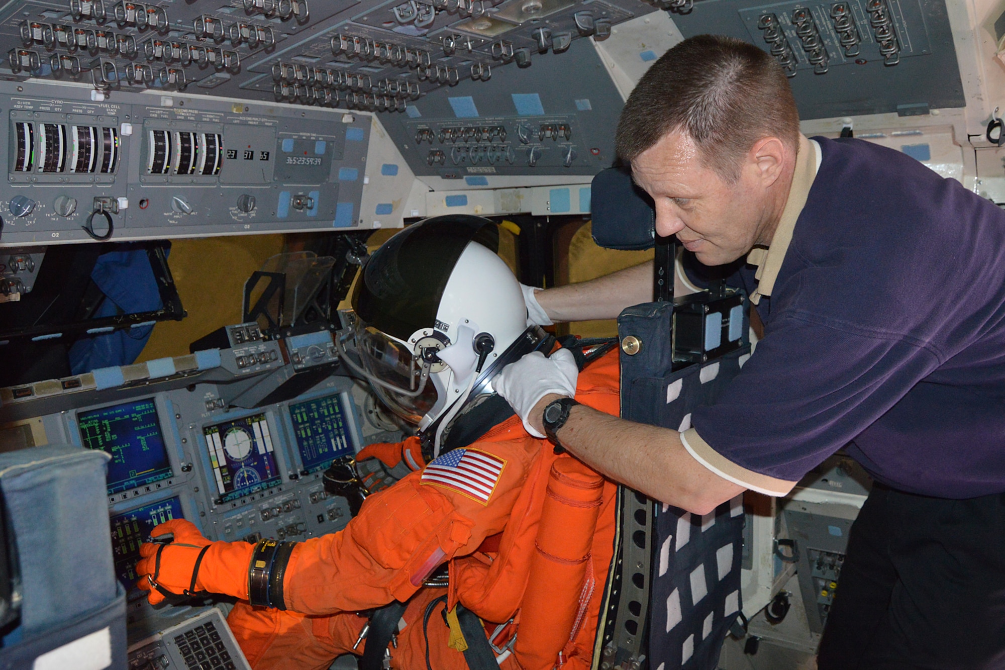 DAYTON, Ohio, --  Museum staff place a mannequin in the pilot seat of the NASA Crew Compartment Trainer. These replica pressure suits represent what astronauts wore during launch & entry. (U.S. Air Force photo)