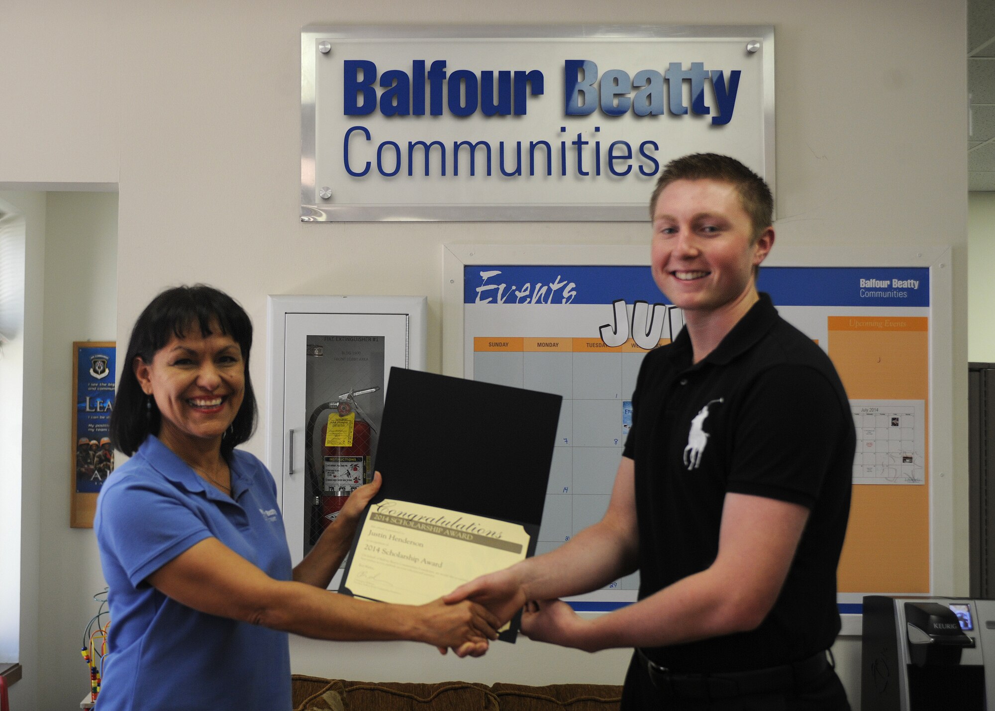 Justin Henderson, son of Chief Master Sgt. Paul Henderson, 27th Special Operations Wing command chief, accepts a certificate of congratulations from Dorothy Molina, Balfour Beatty Communities community manager. The BBC Foundation holds an annual scholarship contest every year for members of the military community. (U.S. Air Force photo/Senior Airman Ericka Engblom)
