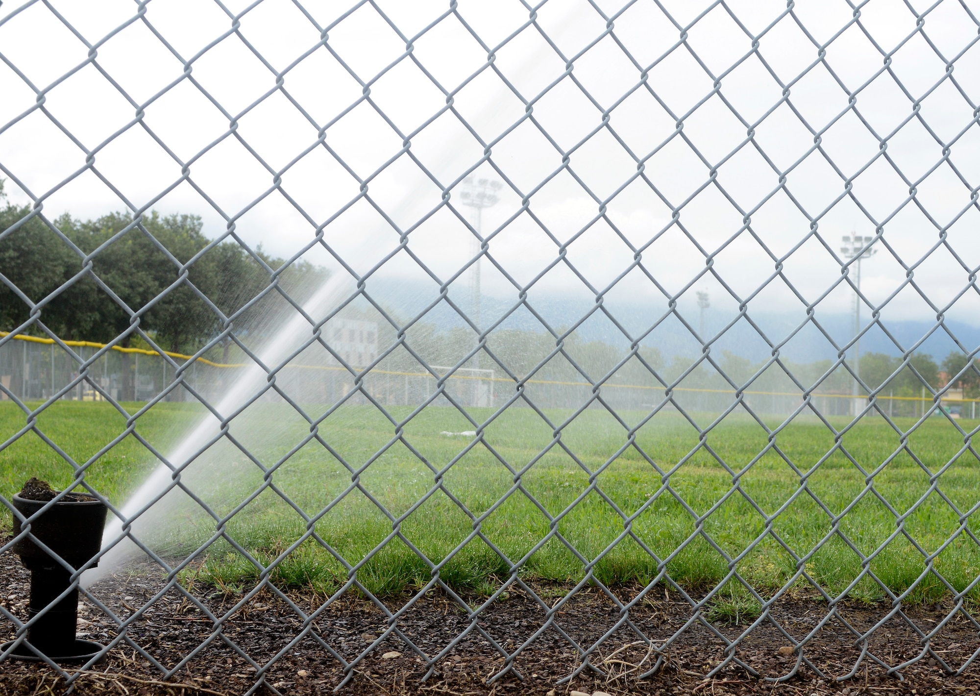 A sprinkler waters a section of a softball field within the sports complex on Area F. Recently, more than eight kilometers of new pipes, 125 sprinklers, new pump stations, an underground holding tank and new automatic controls were installed under the sports complex. The new system saves the base from wasting more than 18,000 gallons of water annually. (U.S. Air Force photo/Staff Sgt. R.J. Biermann)