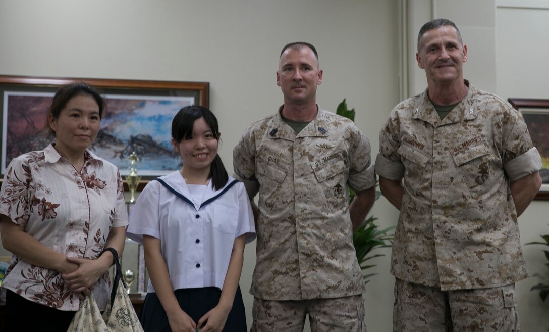 From left to right, Masayo Oshiro, Kanami Oshiro, 1st Sgt. Andre S. Guay and Col. Edmund J. Bowen pose for a photograph after exchanging gifts July 10 at Camp Kinser. Kanami and her mother thanked Guay for saving her life after she was struck by a car June 16. Bowen is the commanding officer of Combat Logisitcs Regiment 37, 3rd Marine Logistics Group, III Marine Expeditionary Force. Guay is the company first sergeant of Food Service Company, CLR-37, 3rd MLG, III MEF. Masayo Oshiro is an agricultural agency worker, and Kanami Oshiro is a student at Ginowan High School. 