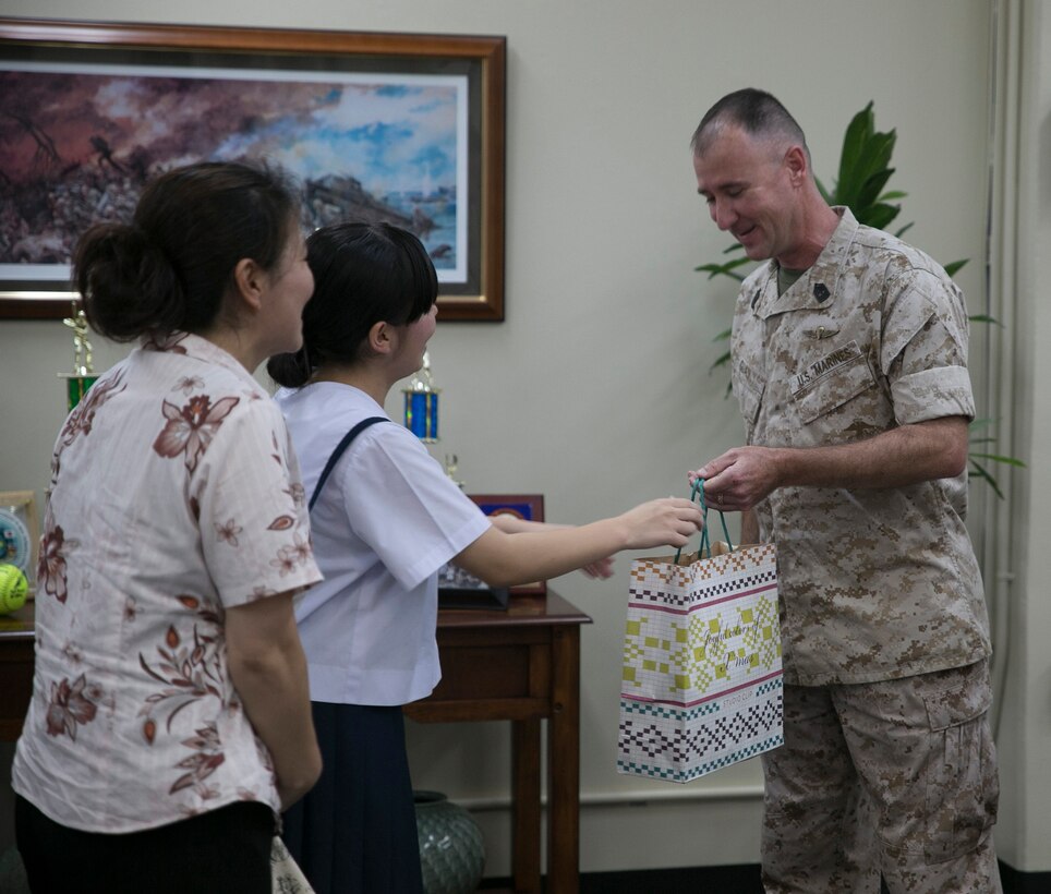Kanami Oshiro, center, with her mother, Masayo Oshiro, left, present a gift to 1st Sgt. Andre S. Guay July 10 at Camp Kinser. Kanami and her mother thanked Guay for saving Kanami’s life after she was struck by a car June 16. Guay is the company first sergeant of Food Service Company, Combat Logistics Regiment 37, 3rd Marine Logistics Group, III Marine Expeditionary Force. Kanami Oshiro is a student at Ginowan High School, and Masayo Oshiro is an agricultural agency worker. 