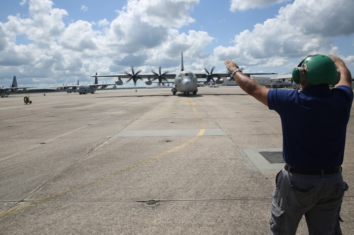 Mike Martinez directs a Kuwait Air Force KC-130J Hercules on the Marine Corps Air Station Cherry Point flight line July 1, 2014. The aircraft arriving here marks a significant training milestone in U.S. – Kuwait military relations. Martinez is a power line mechanic with L-3 Vertex. L-3 Vertex is performing organizational and limited intermediate level maintenance on the new aircraft.