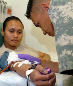 Army Cpl. Christopher LeRoy, of the 932nd Blood Support Detachment, monitors the progress of Army Sgt. Jennifer Skebong, of the 583rd Medlog Company, as she gives blood at Bagram Airfield, Afghanistan. Blood platelets are being collected in country for treatment of critically injured patients.