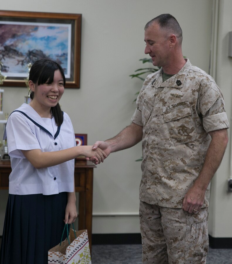 Kanami Oshiro, left, shakes hands with 1st Sgt. Andre S. Guay July 10 at Camp Kinser. Oshiro thanked Guay for saving her life after she was struck by a car June16. Guay is the company first sergeant of Food Service Company, Combat Logistics Regiment 37, 3rd Marine Logistics Group, III Marine Expeditionary Force. Oshiro is a student at Ginowan High School. 
