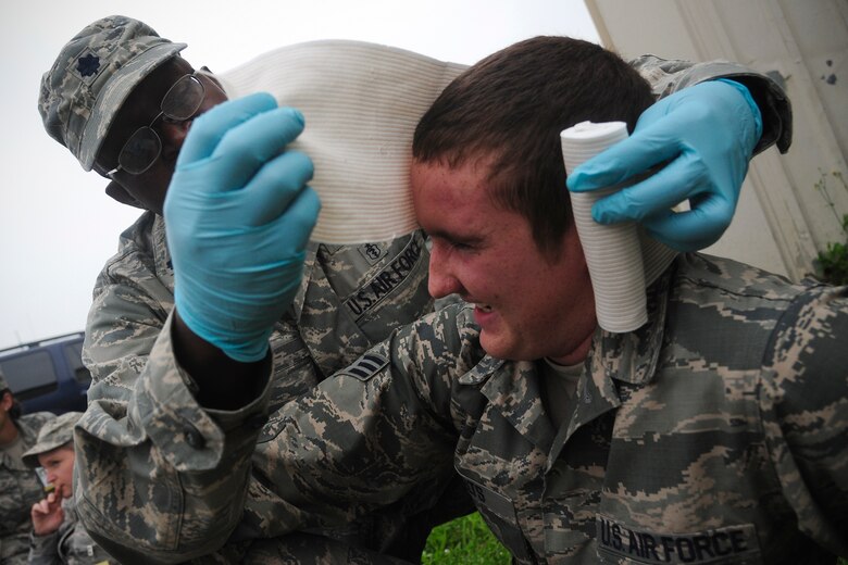 Lt. Col. Joseph Ouma, 8th Medical Group, wraps a bandage around the head of Senior Airman Donald Felts, 8th Aircraft Maintenance Squadron, during exercise Beverly Midnight 14-2 at Kunsan Air Base, Republic of Korea, July 15, 2014. . The Operational Readiness Exercise assesses mission capabilities and ensures the Wolf Pack is in a constant state of readiness.  (U.S. Air Force photo by Senior Airman Taylor Curry/Released)