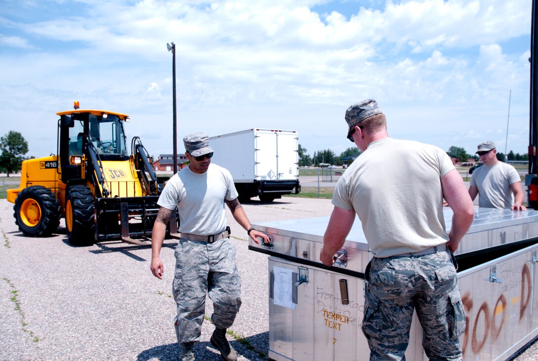 Airmen from the Civil Engineers Squadron open a case containing tent parts. The tents are set up in preparation for Fort D.A. Russell Days. (U.S. Air Force photo by Airman Malcolm Mayfield)