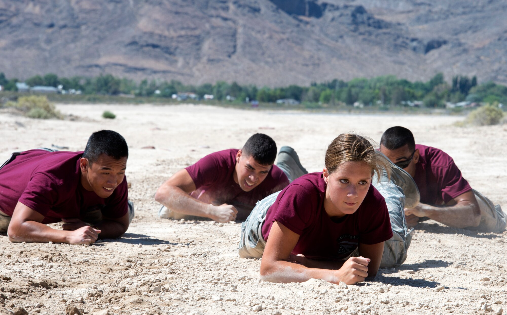 Airmen from the 432nd Aircraft Maintenance Squadron low crawl across a field during the Combat Challenge July 11, 2014, at Creech Air Force Base, Nev.  The Combat Challenge consisted of eight security forces-related challenges such as an M-4 Rifle breakdown and reassembly, team pull-ups, tire flips, low crawls and more.  (U.S. Air Force photo by Tech. Sgt. Nadine Barclay/Released)