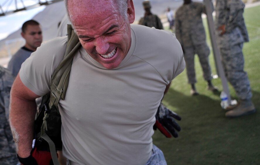 Chief Master Sgt. Butch Brien, 432nd Wing/432nd Air Expeditionary Wing Command Chief, puts on a ruck-sack before a team ruck march during the Combat Challenge July 11, 2014, at Creech Air Force Base, Nev. The Combat Challenge consisted of eight security forces-related challenges such as an M-4 Rifle breakdown and reassembly, team pull-ups, tire flips, low crawls and more. (U.S. Air Force photo by Airman 1st Class Christian Clausen/Released)