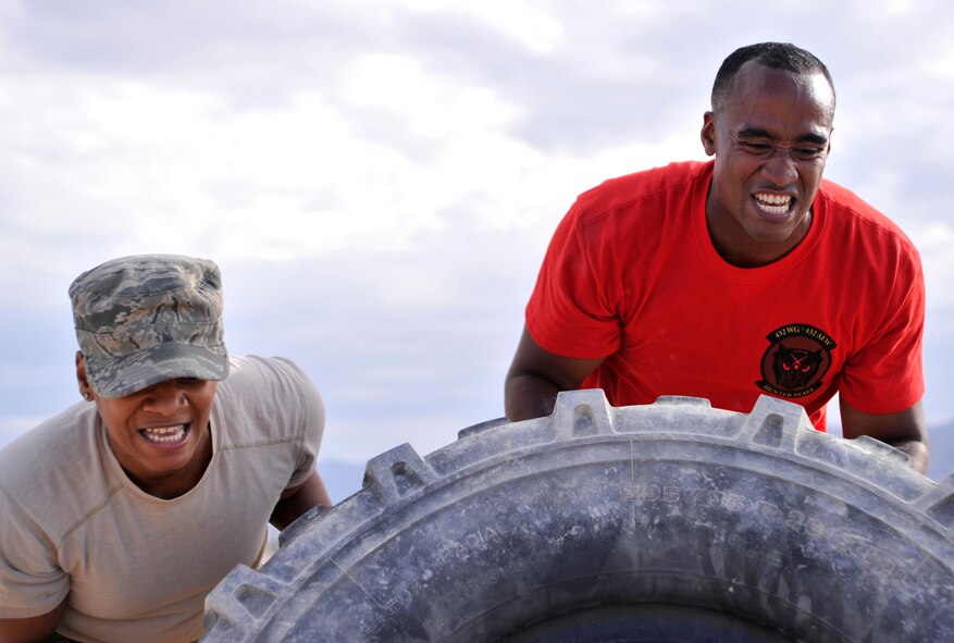Master Sgt. Kiosha Mitchell, 432nd Wing Commander’s Executive Administrations superintendent, left, and Capt. Bishane, 432nd Wing commander’s action group chief, flip a tire during a Combat Challenge July 11, 2014, Creech Air Force Base, Nev. The Combat Challenge was part of the inaugural Creech Combat Dining-In and pitted teams from squadrons around the base against each other in a series of challenges to promote esprit de corps and camaraderie, while providing an opportunity for friendly competition. (U.S. Air Force photo by Airman 1st Class Christian Clausen/Released)