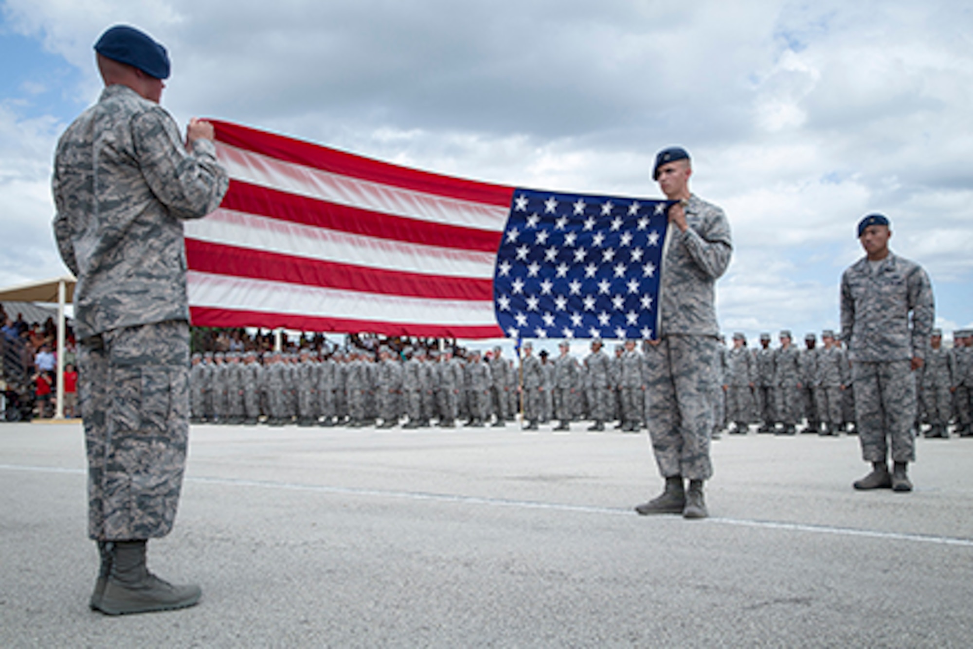 U.S. Air Force Academy Cadet 2nd Class Paul Yang watches two fellow cadets fold the flag during retreat at the basic military training coin ceremony July 10 at Joint Base San Antonio-Lackland. A group of 26 Academy cadets spent six weeks at BMT working with military training instructors as part of the annual Air Education and Training Command Summer Leadership Program. (U.S. Air Force photo/Joshua Rodriguez)