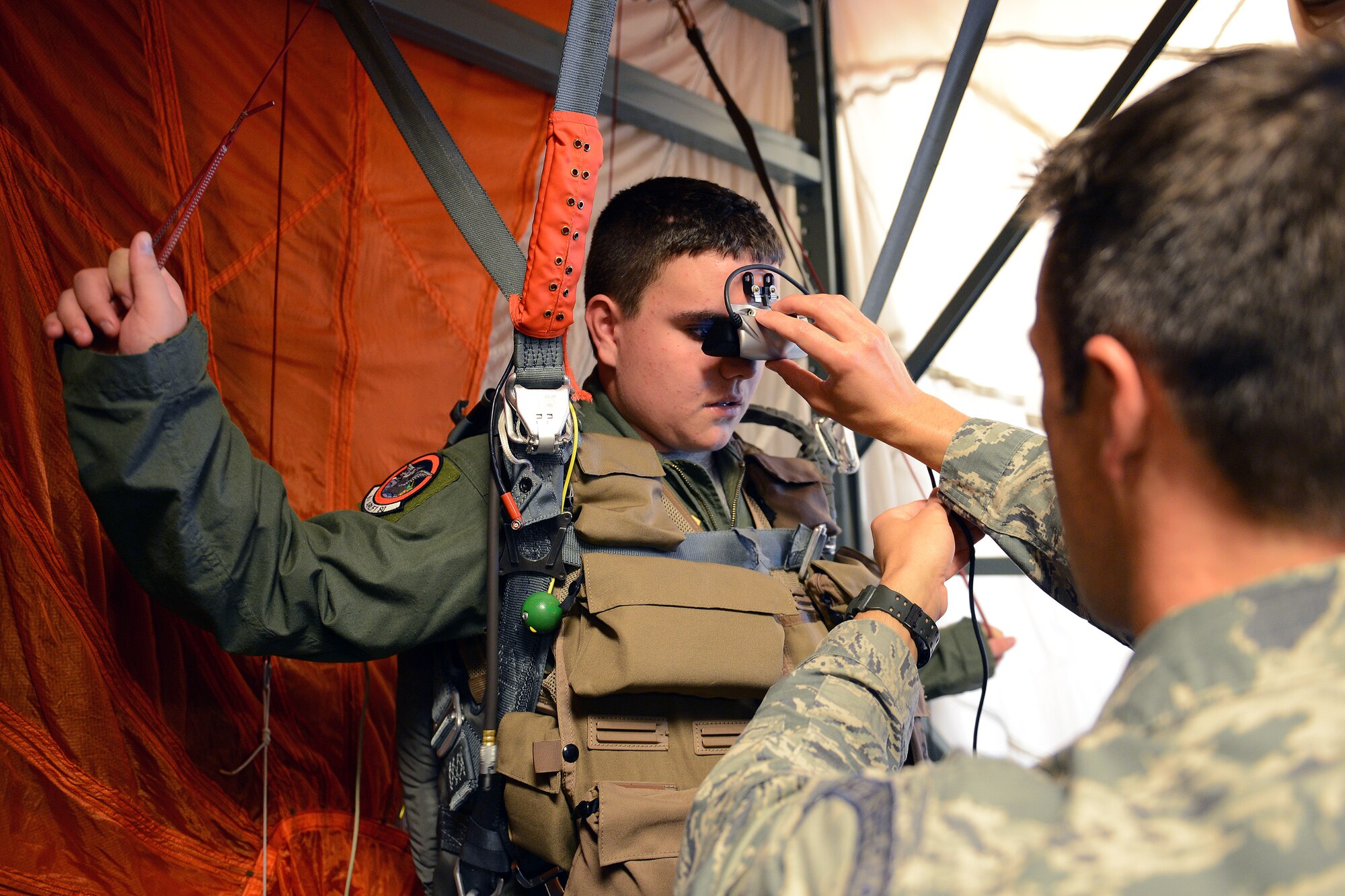 Jerry Connolly(left), pilot for a day, simulates controlling a parachute during a jump using a parachuting simulator under the supervision of Tech. Sgt. Logan Davis, 62nd Operations Support Squadron survival, evasion, resistance, and escape specialist, July 14, 2014, at Joint Base Lewis-McChord, Wash. Connolly simulated parachuting and landing on an aircraft carrier. (U.S. Air Force photo/Airman 1st Class Jacob Jimenez)