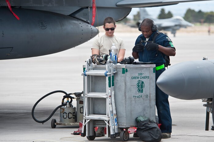 Airman 1st Class Jason Johnson (left) and Staff Sgt. Terrence Byrdsong, 335th Aircraft Maintenance Unit, Seymour Johnson Air Force Base, N.C. jet engine mechanics sign off maintenance forms after correcting discrepancies on an F-15E Strike Eagle during Red Flag 14-3 on July 14, 2014, Nellis AFB, Nev.  The Red Flag exercise involves more than 100 aircraft flying over the 2.9 million acres Nevada Test and Training Range. (U.S. Air Force photo by Lawrence Crespo)