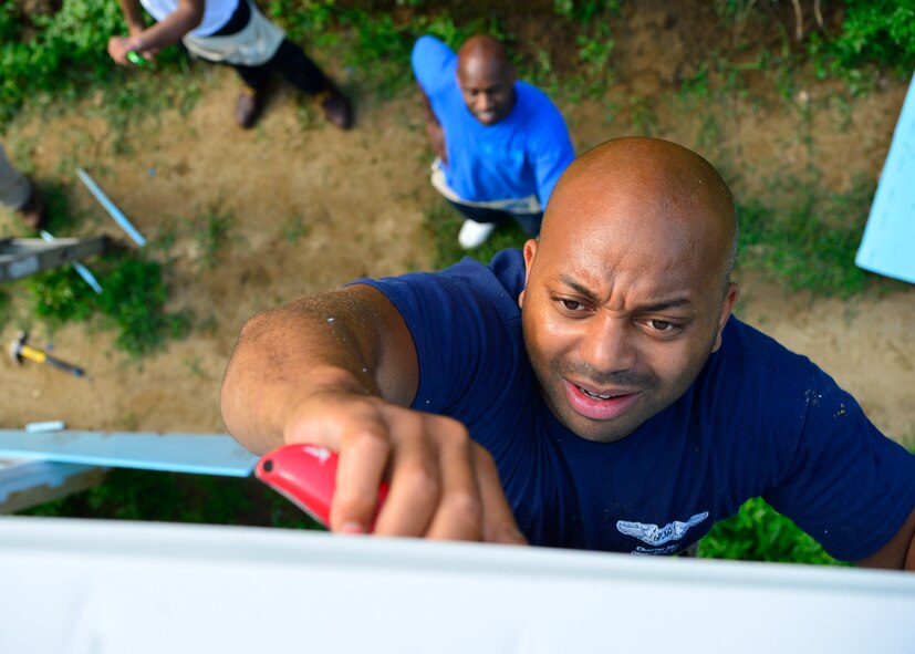Master Sgt. Jamie Beard, 436th Operations Support Squadron aircrew flight equipment flight chief, stands on a ladder as he cuts residential sheathing insulation with an utility knife July 12, 2014, at a Habitat for Humanity construction site in Frederica, Del. Beard, a member of the Air Force Sergeants Association, Chapter 201, was the primary organizer for Team Dover’s participation. (U.S. Air Force photo/Airman 1st Class Zachary Cacicia)