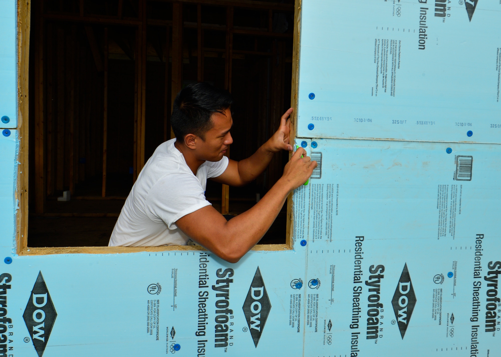 Senior Airman Poler Oliveros, 436th Operations Support Squadron aircrew flight equipment, cuts residential sheathing insulation around a window opening with an utility knife July 12, 2014, at a Habitat for Humanity construction site in Frederica, Del. Oliveros, a Frederica resident, was one of 20 Team Dover Airmen to volunteer. (U.S. Air Force photo/Airman 1st Class Zachary Cacicia)