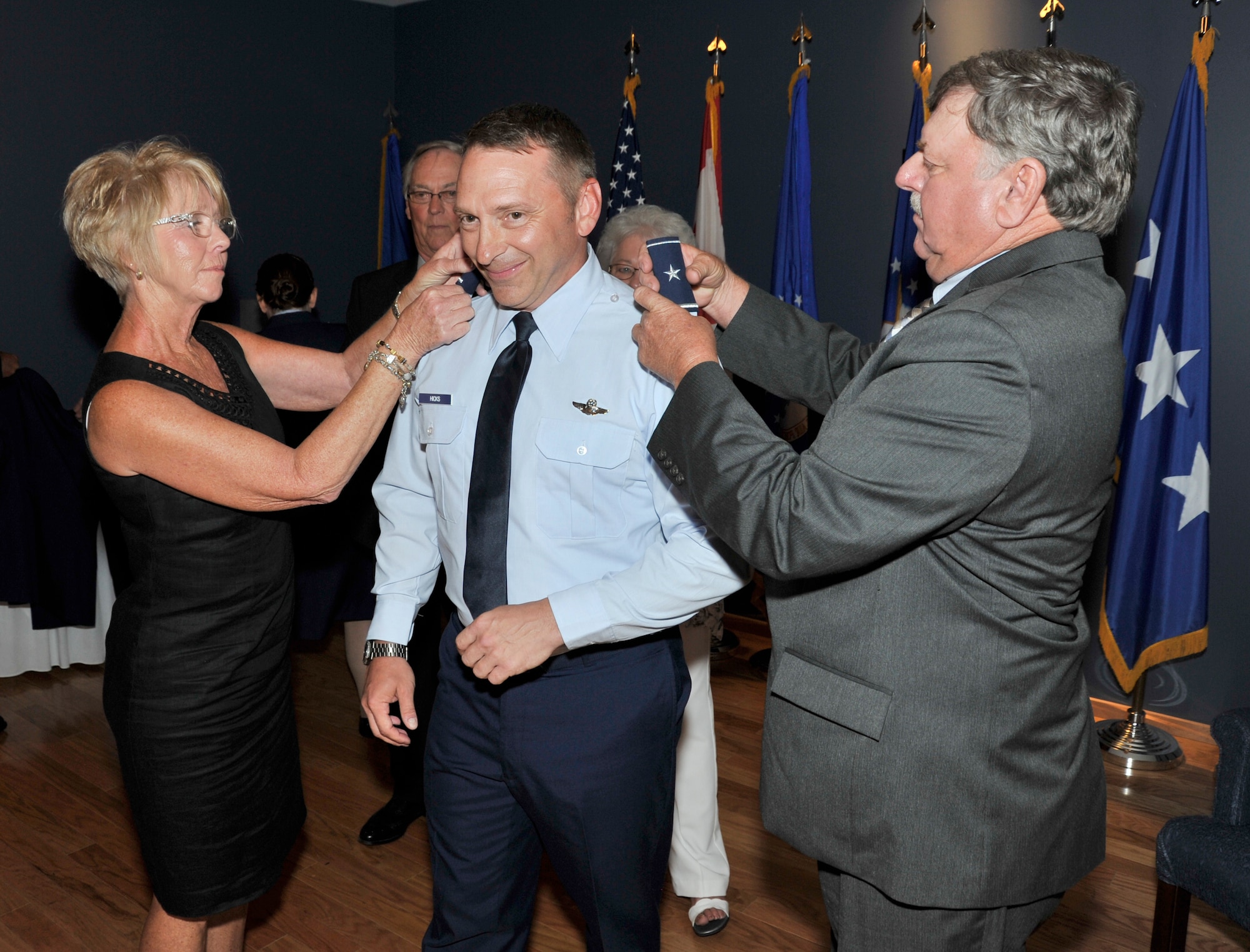 Katrina Hicks, stepmother of newly-promoted Brig. Gen. David Hicks, Air Forces Northern Vice Commander, helps place his new one-star epaulets. Assisting her is family friend Wade Mansfield. (Photo by A1C Sergio Gamboa)