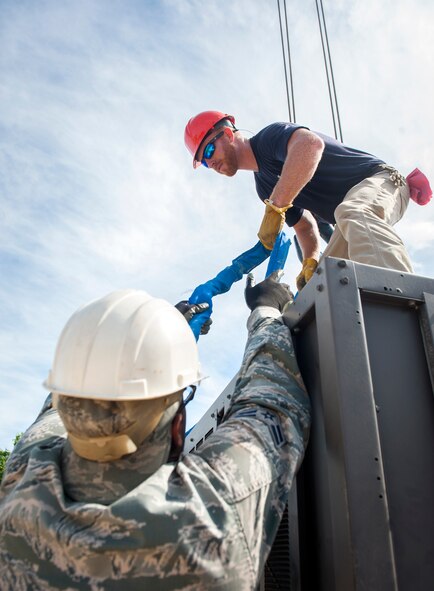 Chris Gaskins, 23d Civil Engineer Squadron heating, ventilation and air conditioning specialist, with assistance from Airman 1st Class Justin Mclendon, 23d CES HVAC journeyman, secures lifting straps to an air-conditioning unit at Moody Air Force Base, Ga., July 14, 2014. From start to finish, the project will take three days to remove the old unit and completely install the new one. (U.S. Air Force photo by Senior Airman Jarrod Grammel/Released)
