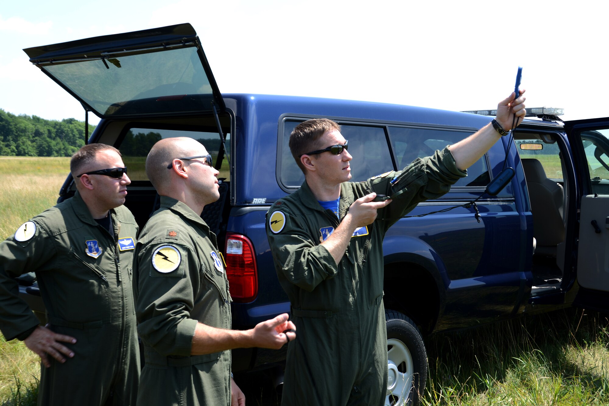 Maj. Chris Thiesing (right), tactics officer with the 118th Airlift Squadron, teaches Maj. Garrett Caponetti (center) how to check the winds at the drop zone using an anemometer during an aerial delivery exercise over Westover Air Reserve Base in Chicopee, Massachusetts, July 12, 2014. Behind them, the malfunction officer, Master Sgt. Corey Kass, a loadmaster with the 118th Airlift Squadron, looks on. These measurements are up-channeled to the crew on a C-130H Hercules aircraft in the skies above so they can make better calculations and drop the cargo on target. (Air National Guard photo by Tech. Sgt. Joshua Mead/Released)