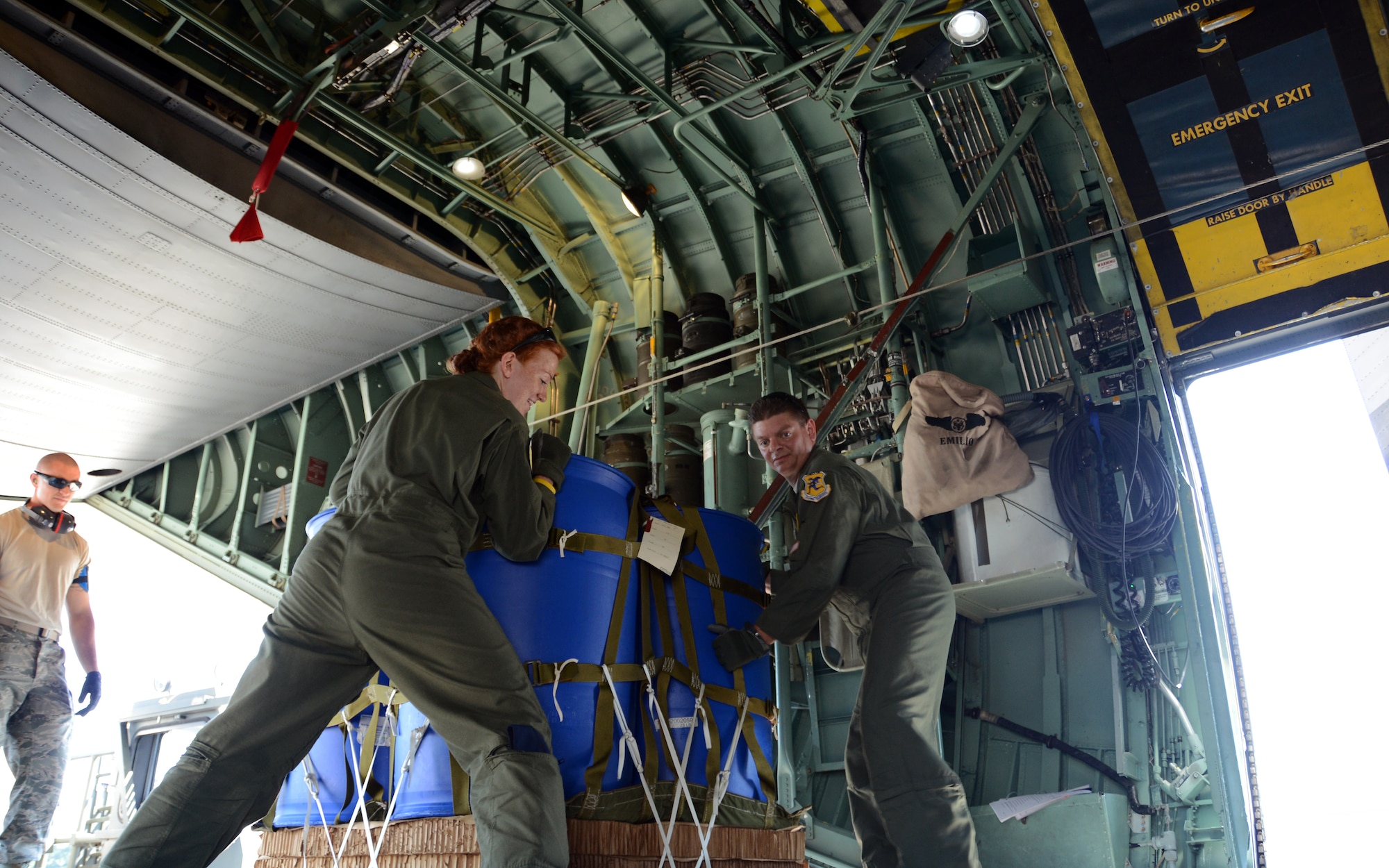 Senior Airman Kaitlin Cardello and Master Sgt. Joseph Amato shift a container delivery system into position on the floor rails of a C-130H Hercules aircraft during an air drop exercise at Bradley Air National Guard Base, East Granby, Connecticut on July 12, 2014. The exercise started with Airmen like Senior Airman Joseph Hamel (far left) loading the CDS onto a transport vehicle and transferring it onto the C-130H. From there, the loadmasters secure and position the load for air delivery. (Air National Guard Photo by Tech. Sgt. Joshua Mead/Released)