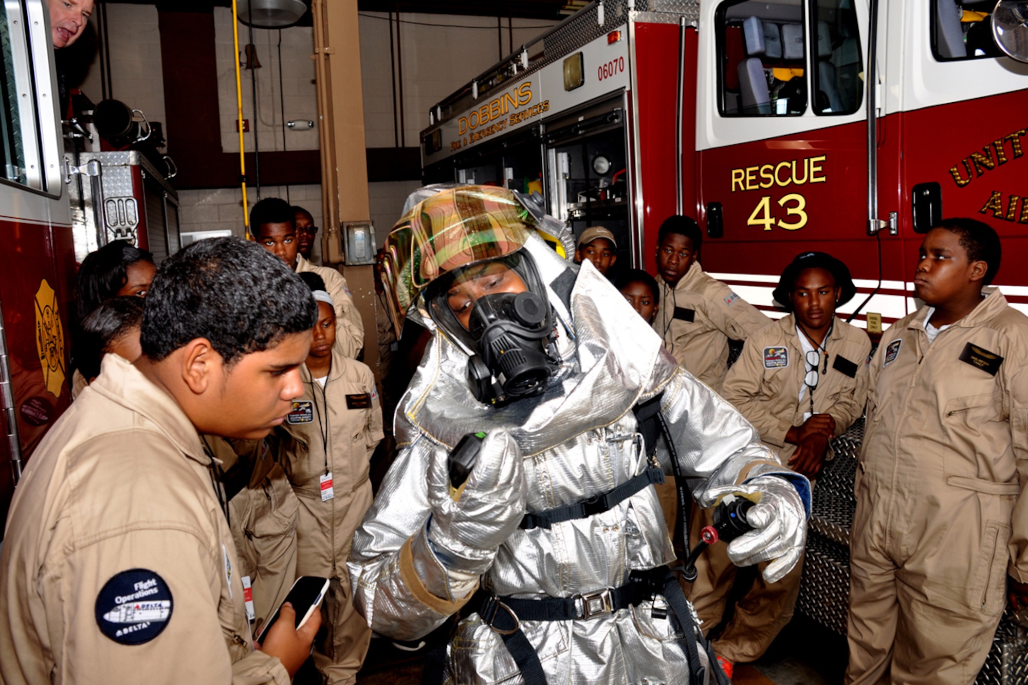 Airman Christa Dennis of the Dobbins Fire Department demonstrates the wearing of a protective firefighter suit during the Tuskegee Airmen Aviation Career Training cadet visit to Dobbins Air Reserve Base June 24, 2014. (Photo by Donald Alexander)