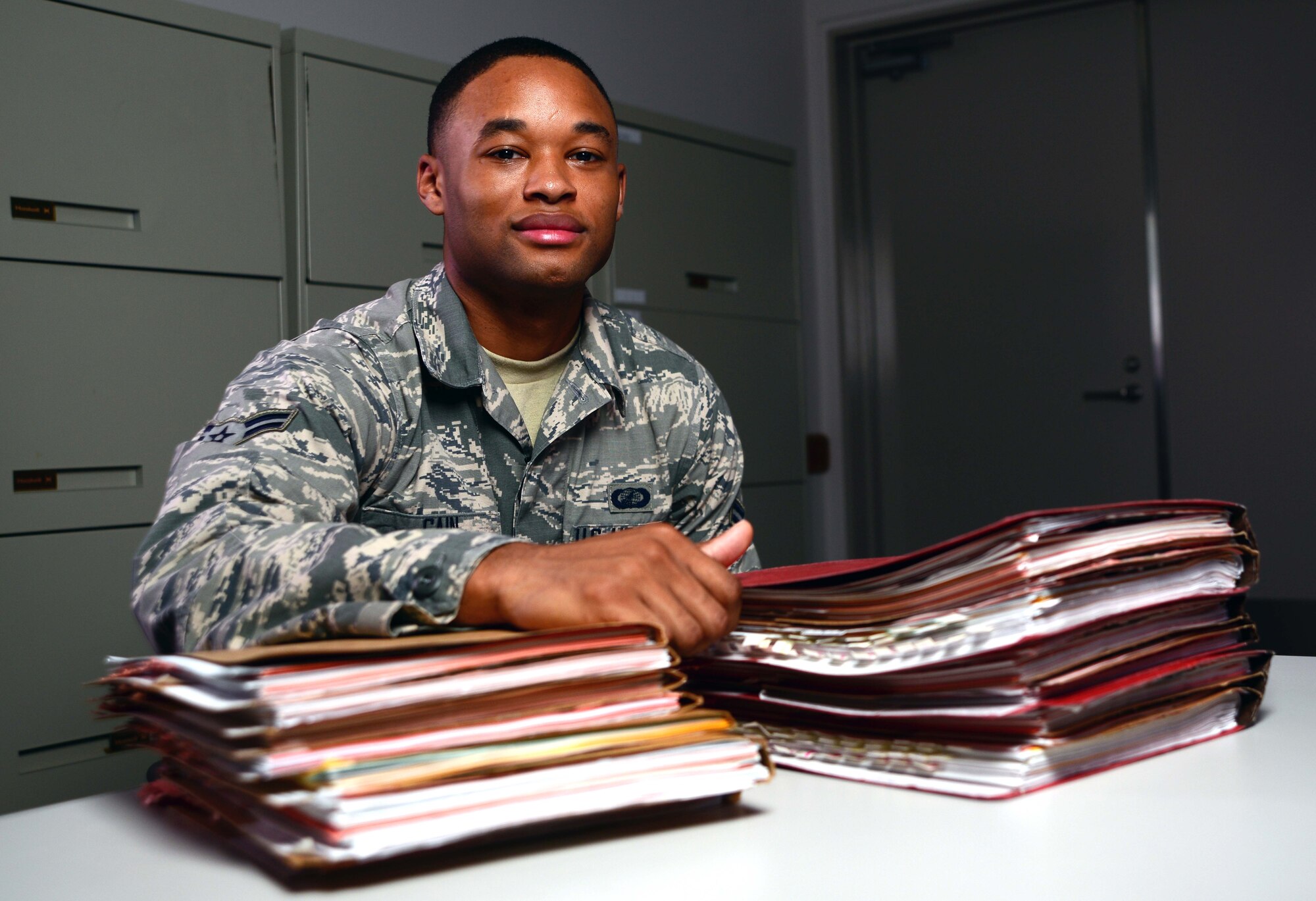 Airman 1st Class Teante Cain, 35th Contracting Squadron contracting specialist, sits with a stack of contracts he processed at Misawa Air Base, Japan, July 14, 2014. Cain manages and administrates multiple contracts for several units on a daily basis, and was named Misawa's Wild Weasel of the Week. (U.S. Air Force photo/Senior Airman Derek VanHorn)