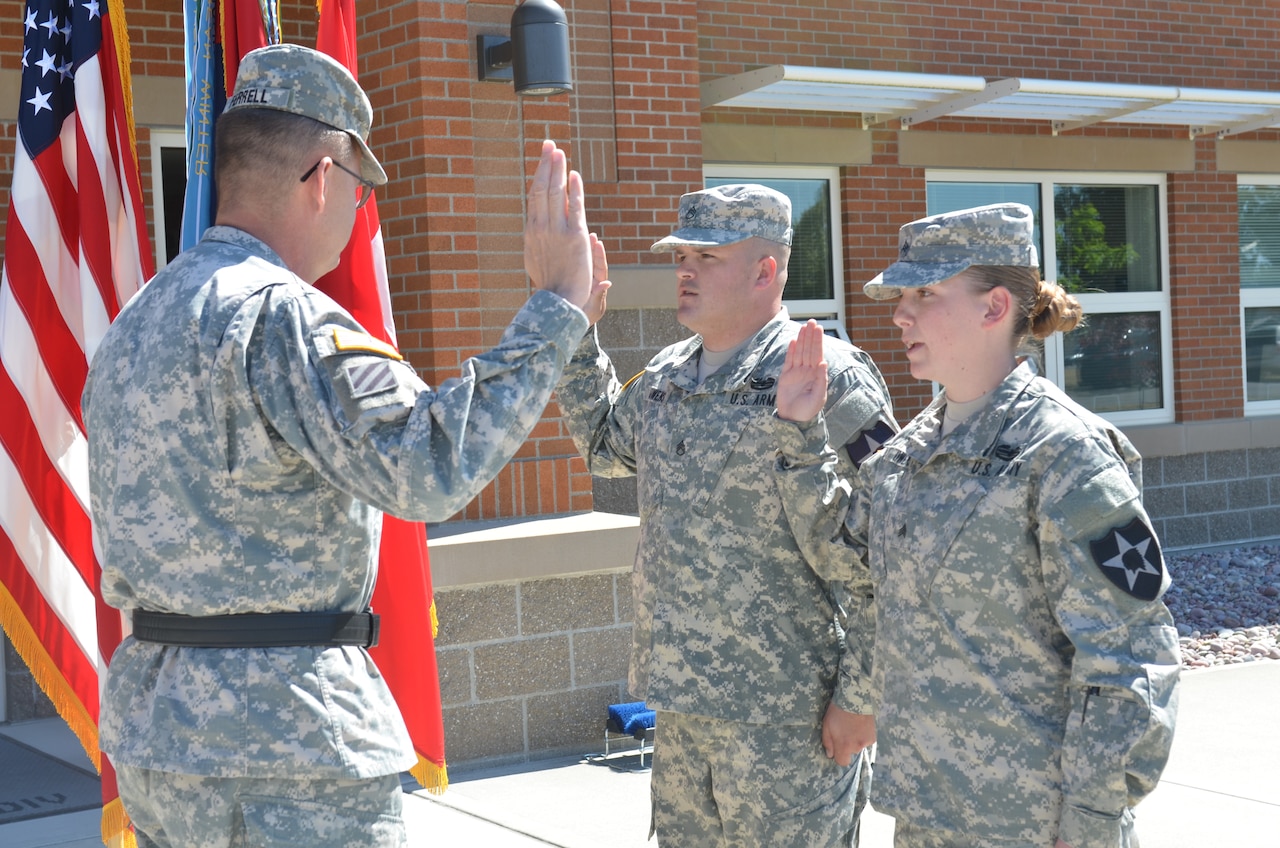 Army Maj. Gen. Terry Ferrell, left, 7th Infantry Division commanding general, administers the re-enlistment oath to Army Staff Sgt. James Owens, center, and Army Sgt. Brook Owens, right, at Joint Base Lewis-McChord, Wash., July 10, 2014.  U.S. Army photo by Staff Sgt. Chris McCullough