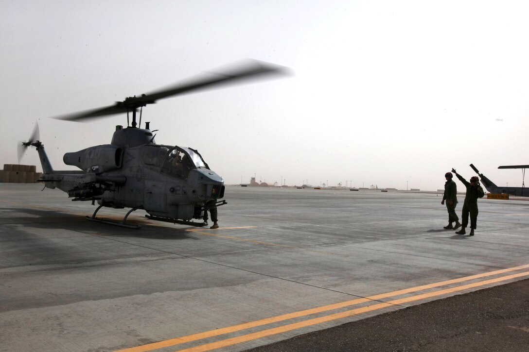 U.S. Marines troubleshoot an AH-1W Cobra helicopter before a mission on Camp Bastion, Afghanistan, July 3, 2014.
