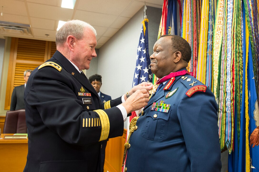 U.S. Army Gen. Martin E. Dempsey, chairman of the Joint Chiefs of Staff, presents Kenya's Chief of Defense Forces Gen. Julius Waweru Karangi with a Legion of Merit during an award presentation at the Pentagon, July 15, 2014. 