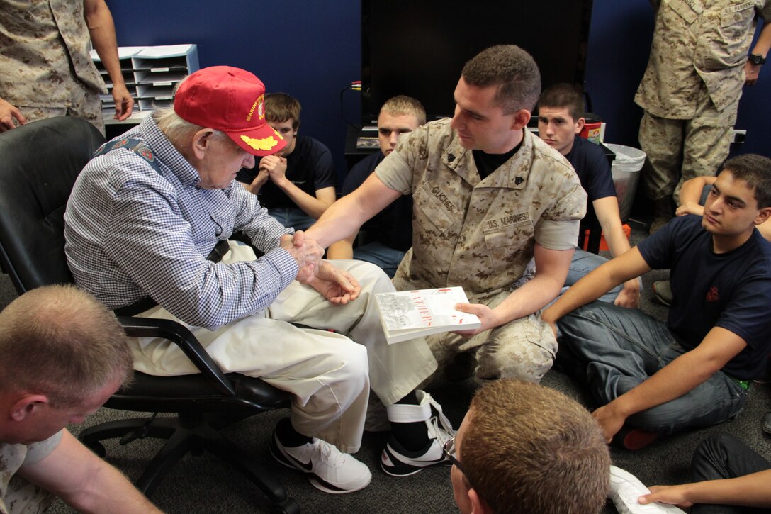 Pfc. William Faulkner, a World War II veteran, handed out signed copies of The Flags of Our Fathers to Marines during a meet and greet with poolees from Recruiting Sub-station Aurora, Recruiting Station Chicago, July 12.