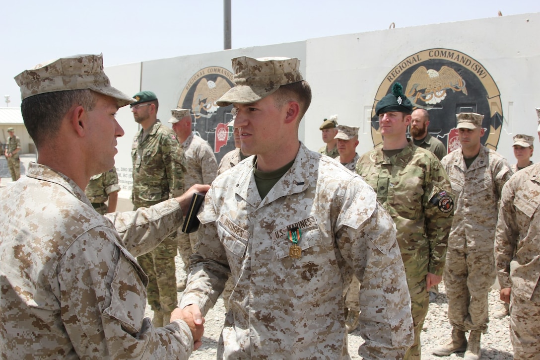 U.S. Marine Col. Morgan Mann, left, Security Force Assistance Coordinator, Regional Command (Southwest), shakes hands with 1st Lt. Joshua Bridges, right, after pinning a  a Navy and Marine Corps Achievement Medal Bridges' uniform during a ceremony aboard Camp Leatherneck, Helmand province, Afghanistan, July 13, 2014. Bridges, a native of Morganton, N.C., and assessments and plans officer, RC(SW), deployed to Helmand province during Jan. 2014 and was vital to RC(SW) planning efforts during the 2014 Afghan presidential elections and the upcoming transition of full security responsibility to the Afghan National Security Forces in the region by the end of 2014.