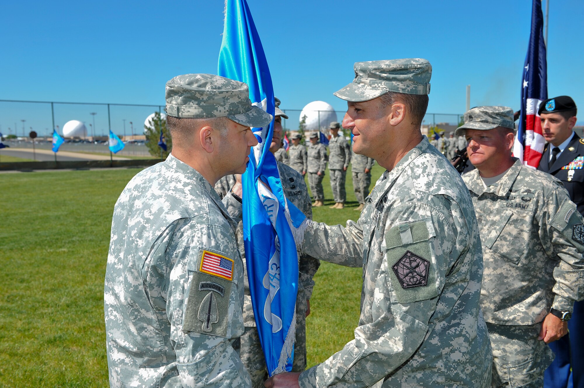 Col. Anthony Hale, 704th Military Intelligence Brigade commander, left, receives the 743rd Military Intelligence Battalion guidon from Lt. Col. Gary Hausman signifying his relinquishing of command June 19, 2014, at the softball fields on Buckley Air Force Base, Colo. During the ceremony Lt. Col. Andrew Pelka, 743rd MI Battalion commander, assumed command from Hausman after two years of service to the unit. (U.S. Air Force photo by Senior Airman Phillip Houk/Released)
