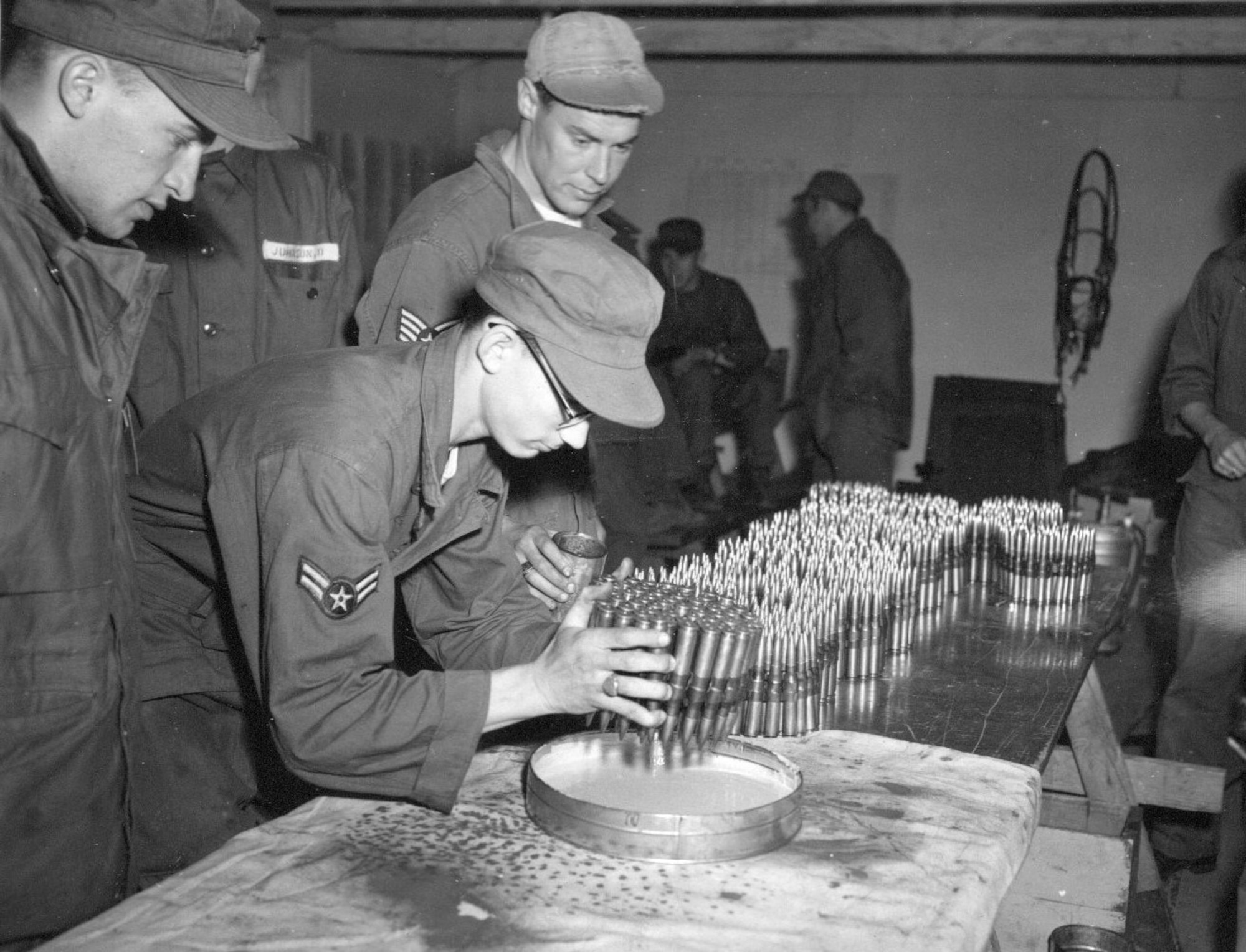 An Airman dips the tips of .50-caliber machine gun ammunition in colored paint for use in aerial gunnery training by 142nd Fighter-Interceptor Group F-86 Sabre jet fighter pilots during annual training at Gowen Field, Idaho,  June 17, 1954 (Courtesy 142FW History Archives)