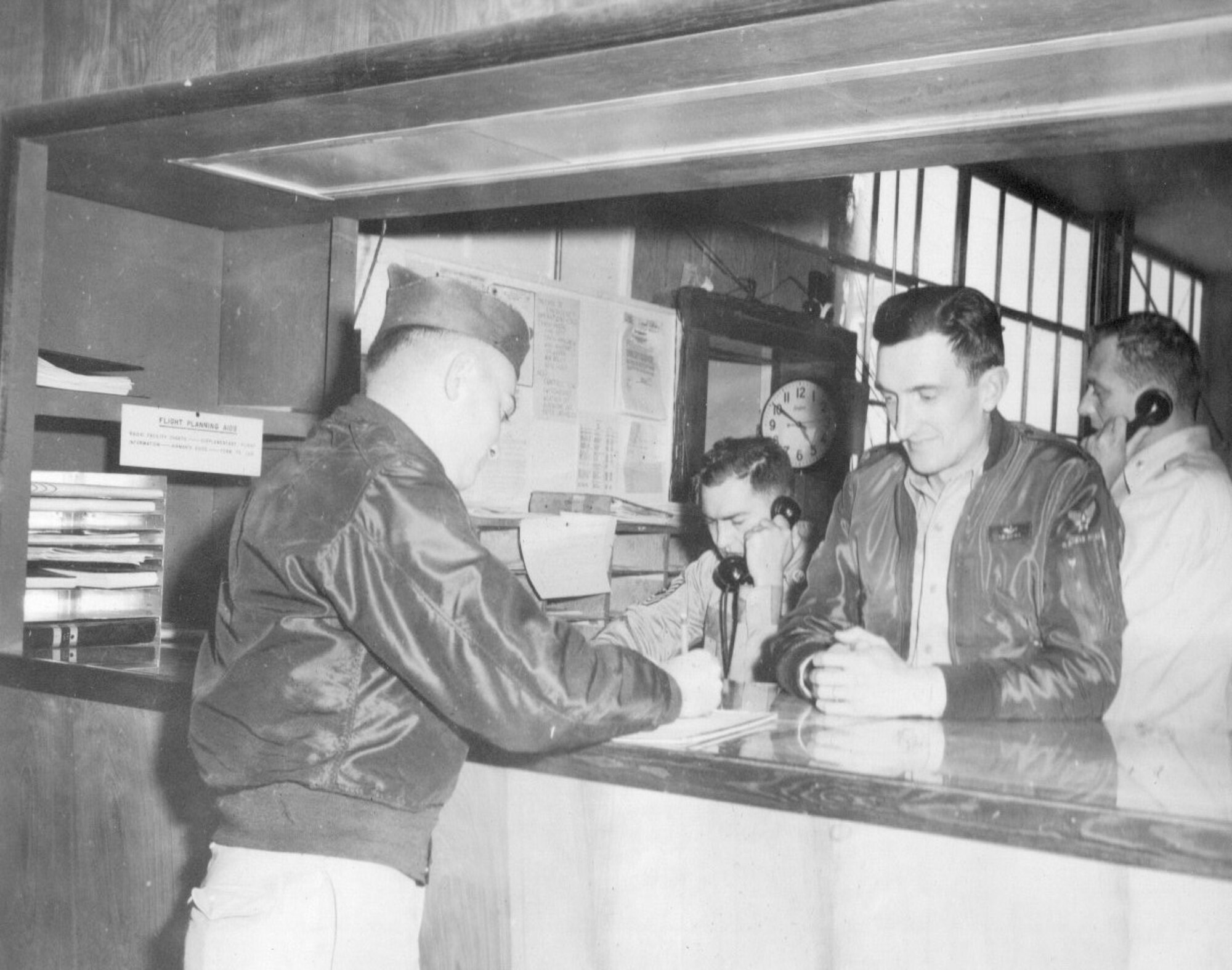 An unidentified aircrew member signs a document on the operations desk at Gowen Field, Idaho, as the Commander, 142nd Fighter-Interceptor Group, Lt. Col. Staryl C. Austin, Jr., looks on, June 18, 1954. (Courtesy 142FW History Archives)