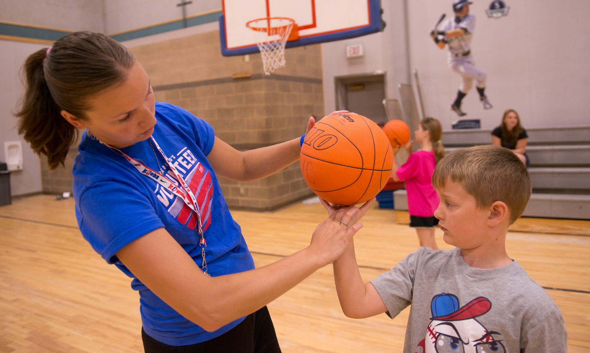 Erin Arel, 366th Force Support Squadron Youth Center sports and fitness director, helps a child improve his bank shot July 15, 2014, at Mountain Home Air Force Base, Idaho. “The purpose behind the basketball clinics was to introduce and enhance the youth’s skills,” said Arel. (U.S. Air Force photo by Airman 1st Class Malissa Lott/RELEASED)