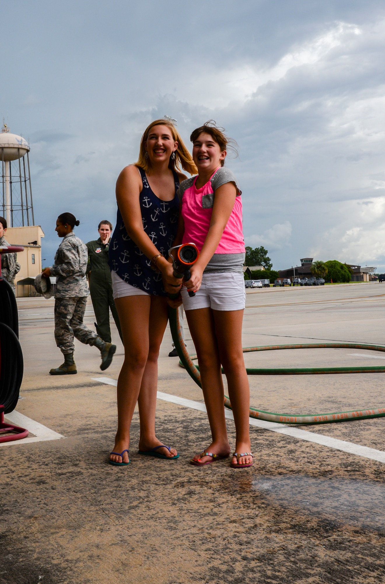 Kristen, left, and Alexis Ramer prepare to spray their father, U.S. Air Force Col. Steve Ramer, with a hose at Moody Air Force Base, Ga., July 15, 2014. It is traditional to spray a pilot with water or champagne after final or “fini” flights. (U.S. Air Force photo by Airman 1st Class Sandra Marrero/Released).  

