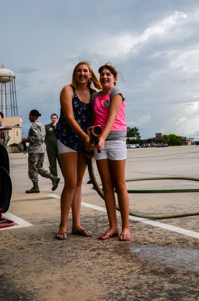 Kristen, left, and Alexis Ramer prepare to spray their father, U.S. Air Force Col. Steve Ramer, with a hose at Moody Air Force Base, Ga., July 15, 2014. It is traditional to spray a pilot with water or champagne after final or “fini” flights. (U.S. Air Force photo by Airman 1st Class Sandra Marrero/Released).  
