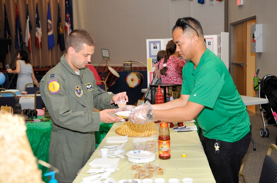 Captain Frank Janes, 2nd Aerospace Medical Squadron, takes a cup of pad thai from Staff Sgt. Jan Sanchez, Asian-Pacific Islander club photographer at the Sixth Annual Multicultural Day celebration on Barksdale Air Force Base, La., July 11, 2014. The Asian-Pacific Islander booth also provided food samples of spring rolls and sauces from various parts in Asia. (U.S. Air Force photo/Airman 1st Class Benjamin Raughton)