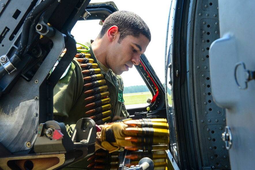 U.S. Air Force Staff Sgt. Justin Ramirez, 41st Rescue Squadron special missions aviator, loads .50-caliber bullets into a machine gun on an HH-60G Pave Hawk at Moody Air Force Base, Ga., July 10, 2014. While deployed, Ramirez uses the machine gun to defend the HH-60. (U.S.  Air Force Airman 1st Class Ceaira Tinsley/Released)
