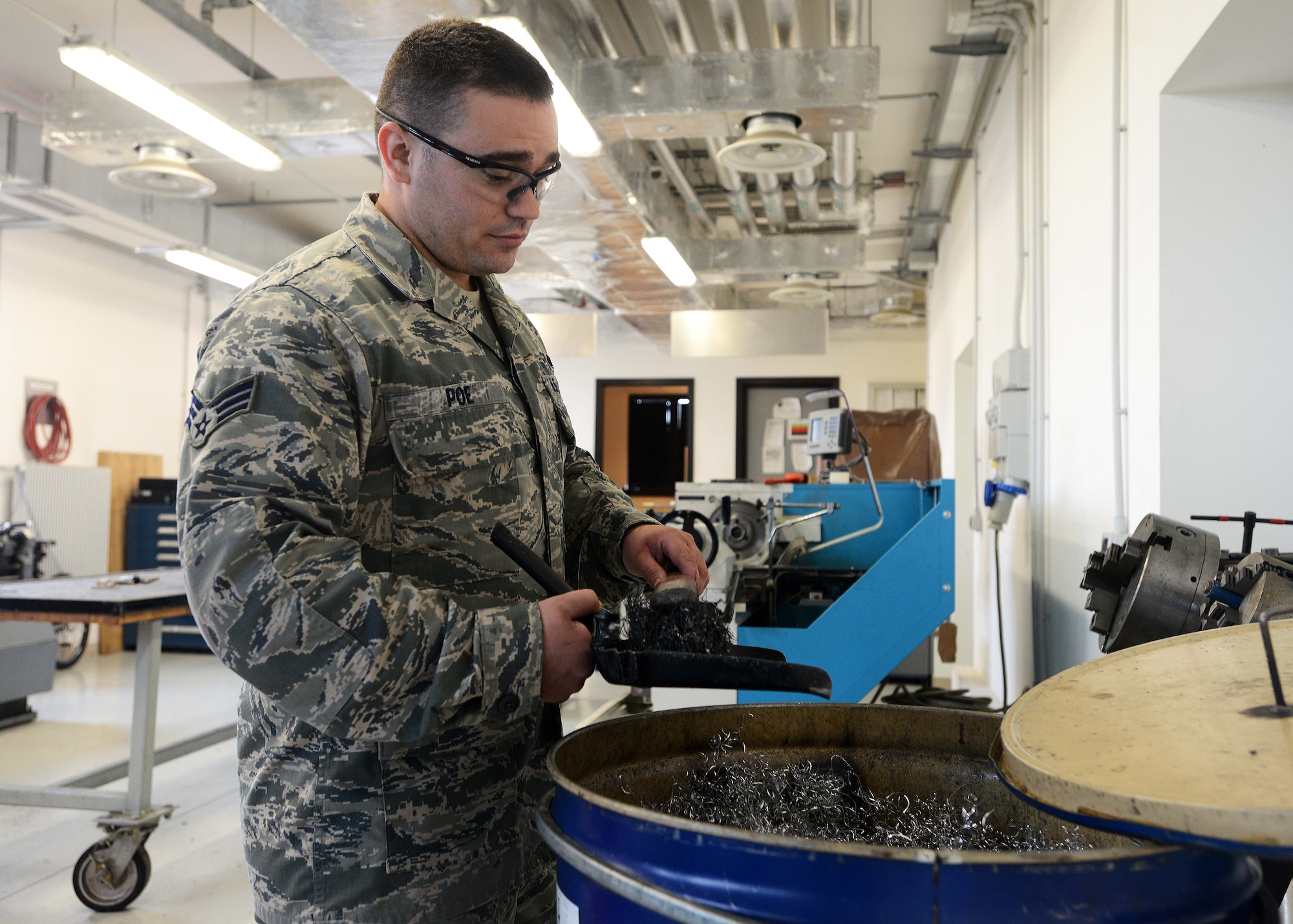 Senior Airman Troy Poe, 31st Maintenance Squadron metals technology journeyman, discards excess metal shavings, July 9, 2014, at Aviano Air Base, Italy. Common jobs that metal technologists receive are making bushings, which are stationary bearings that are a crucial part of aircraft. (U.S. Air Force photo/Airman 1st Class Deana Heitzman)