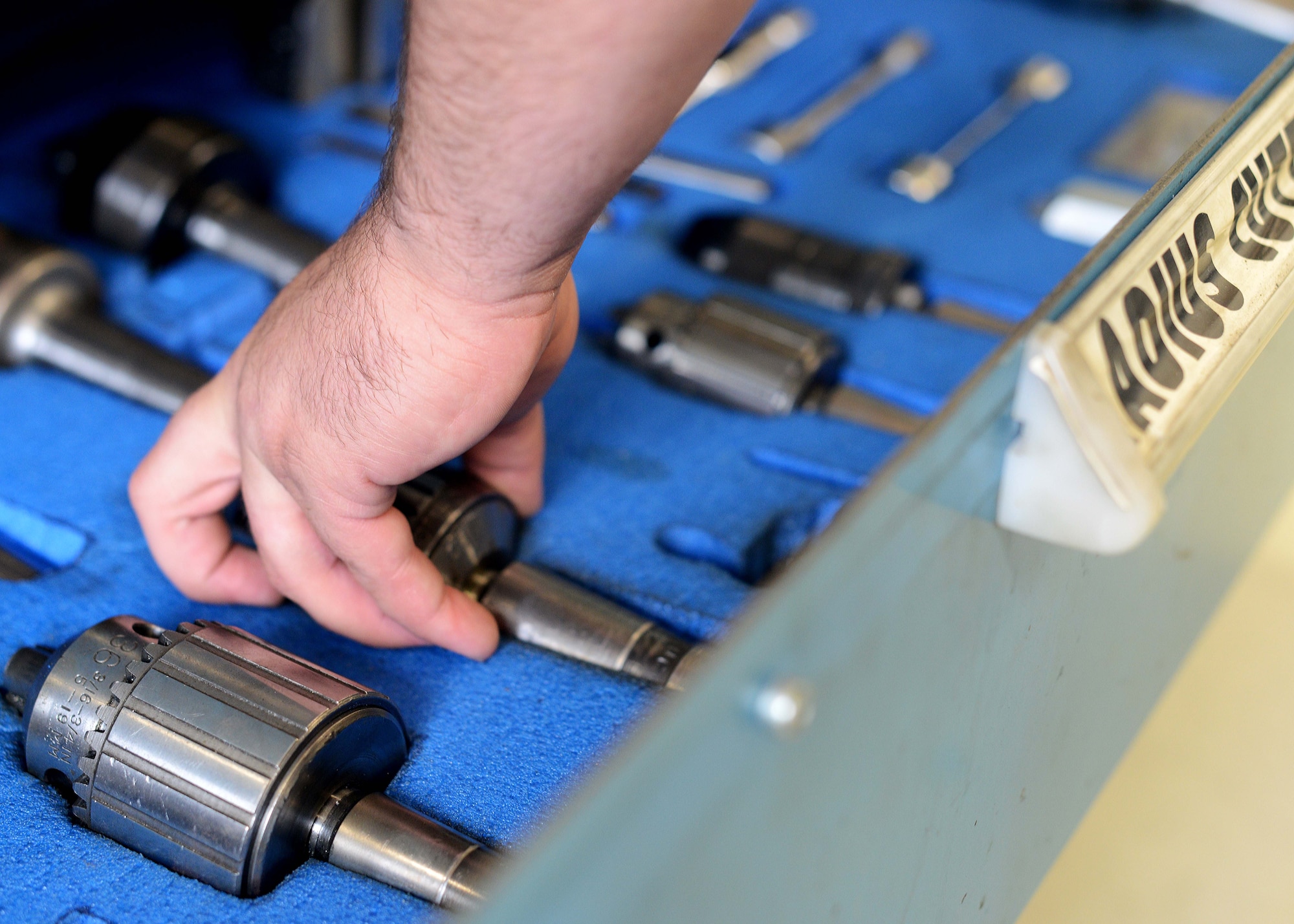 Senior Airman Troy Poe, 31st Maintenance Squadron metals technology journeyman, selects a lathe radius cutter to perform sanding, July 9, 2014, at Aviano Air Base, Italy. Metals technicians are certified in seven different types of metal to include mild steel, stainless steel and aluminum. (U.S. Air Force photo/Airman 1st Class Deana Heitzman)  