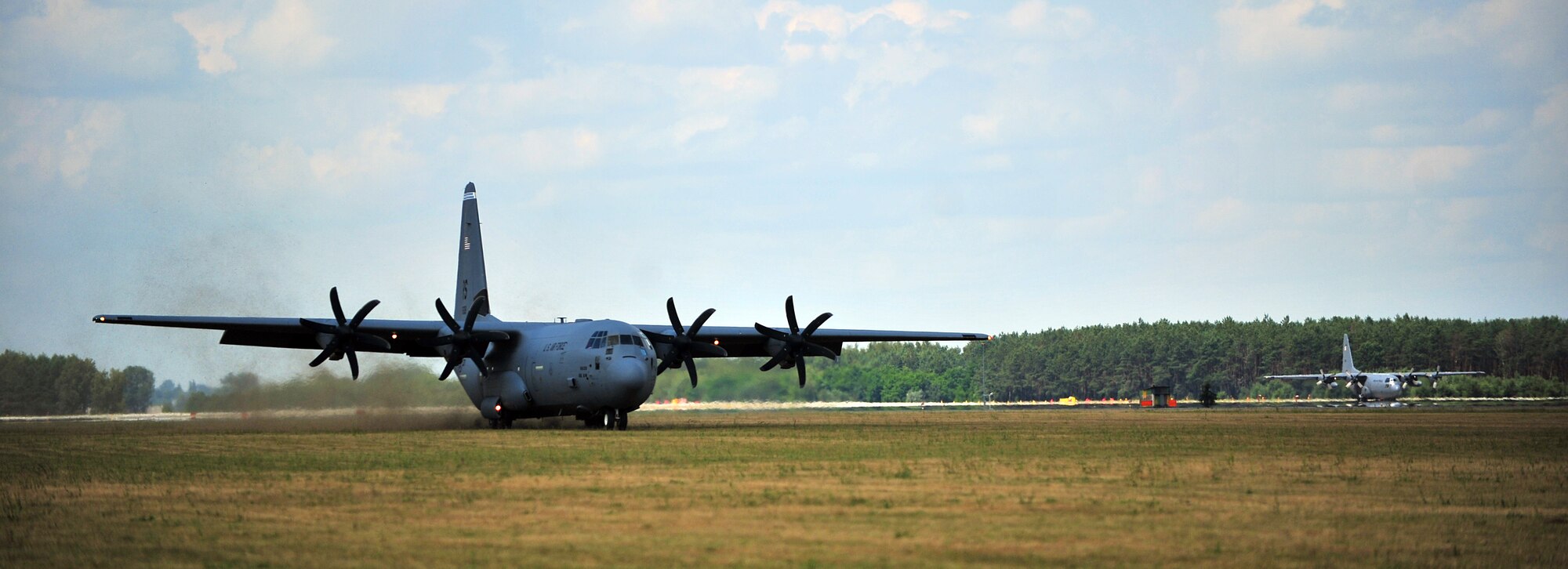 A U.S. Air Force C-130J Super Hercules from Ramstein Air Base, Germany, performs a grass landing during a training deployment at Powidz Air Base, Poland, July 11, 2014. Airmen from the 86th Airlift Wing are located in Poland for a forward training deployments employing training events with our NATO allies demonstrating shared commitments to peace. (U.S. Air Force photo by Senior Airman Christine Griffiths/Released)