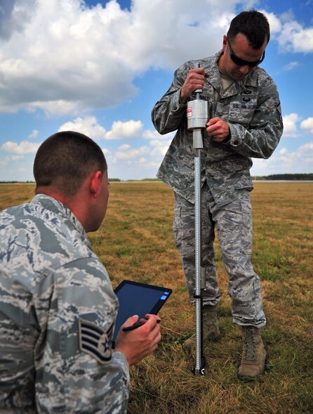 Master Sgt. Stanley MacDonald, 435th Aircraft Maintenance Squadron air traffic controller, and Staff Sgt. Brock Neel, 435th Aircraft Maintenance Squadron engineer, survey an area for training with a dynamic cone penetrometer at Powidz Air Base, Poland, July 1, 2014. The measurement from the DCP is one of the steps in determining if an airfield is safe for an aircraft landing. Airmen from the 86th Airlift Wing are located in Poland for a forward training deployments employing training events with our NATO allies demonstrating shared commitments to peace. (U.S. Air Force photo by Senior Airman Christine Griffiths/Released)
